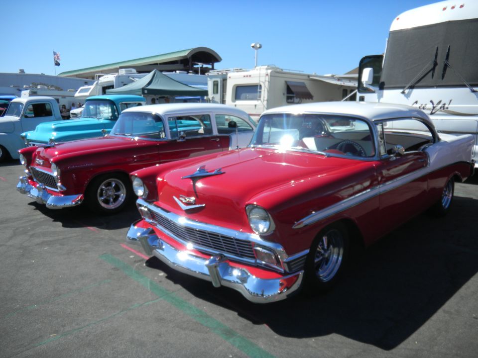 Red and white 1956 Chevrolet Bel Air coupe parked next to a red and white 1956 Chevrolet sedan
