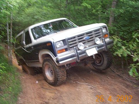 1986 Ford Bronco - This 1986 Ford Bronco navigates a challenging off-road path through a wooded area.