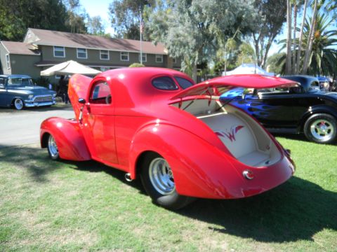 1997 Ford Ranger - A bright red custom coupe with its hood and trunk open sits on display at an outdoor car show.