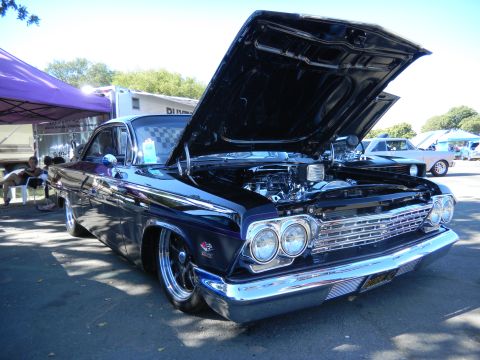 1997 Ford Ranger - A customized classic car is displayed with its hood open, revealing a powerful engine, at an outdoor event.