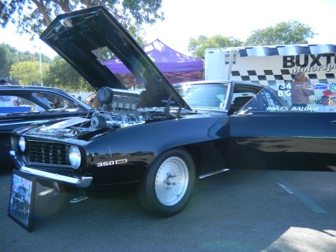 1997 Ford Ranger - A black muscle car with its hood open, revealing a powerful engine, sits at an outdoor event.