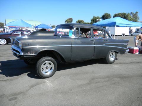 1997 Ford Ranger - A modified 1957 Chevrolet Bel Air is displayed at an outdoor event, with other vehicles and tents in the background.