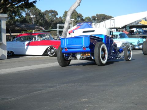 1997 Ford Ranger - A custom blue hot rod pickup truck is seen from the rear, parked alongside other classic vehicles at a car show.
