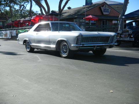 1997 Ford Ranger - A classic silver Buick Riviera is parked on a street in front of a building with outdoor seating.