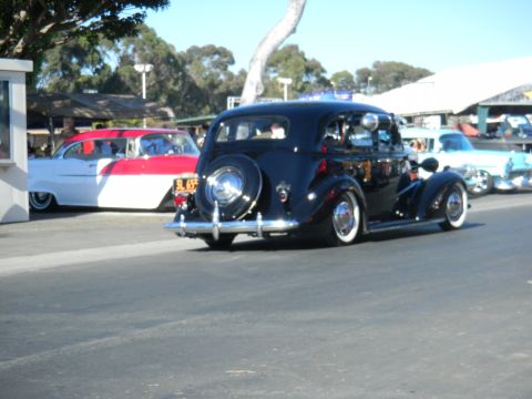 1997 Ford Ranger - A black vintage car with a spare tire mounted on the rear is seen at a car show, with other classic vehicles in the background.