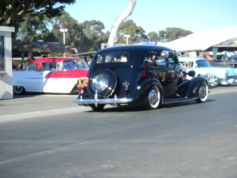 Black vintage car with spare tire on rear, white wall tires, and chrome bumper