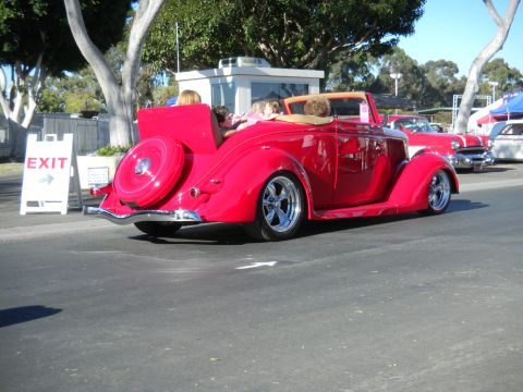 1997 Ford Ranger - A red convertible hot rod with a spare tire on the rear is parked outdoors with other vehicles.