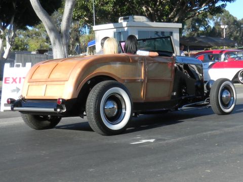 1997 Ford Ranger - A classic woodie hot rod with whitewall tires is parked next to a red and white car.