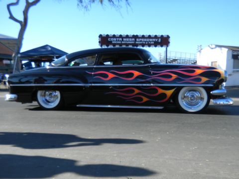 1997 Ford Ranger - A classic black hot rod with vibrant flame decals is parked outdoors under a clear blue sky.