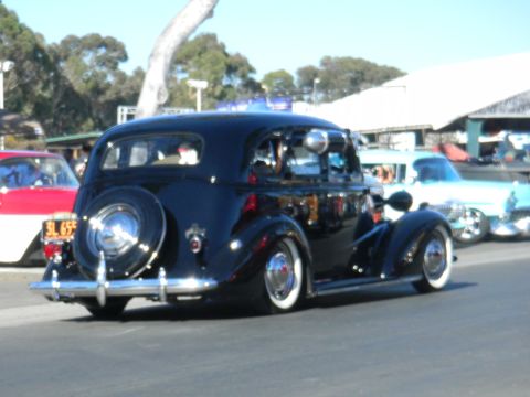 1997 Ford Ranger - A black vintage sedan is parked next to other classic cars at an outdoor event.