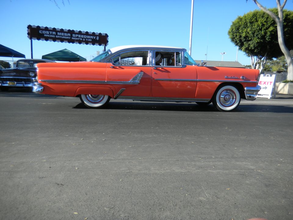 Orange and white 1955 Mercury Montclair sedan, side view, chrome trim, whitewall tires, parked