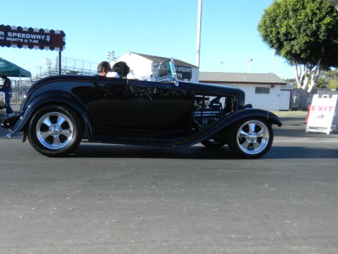 1997 Ford Ranger - A black hot rod roadster is seen from the side, an exposed engine and chrome wheels, at a cruise event.