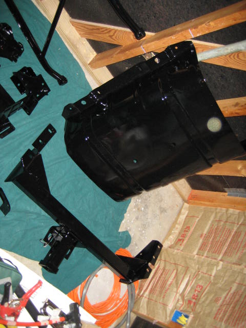 1988 Ford Bronco - Various black painted vehicle frame parts are arranged on a teal cloth and wooden supports.