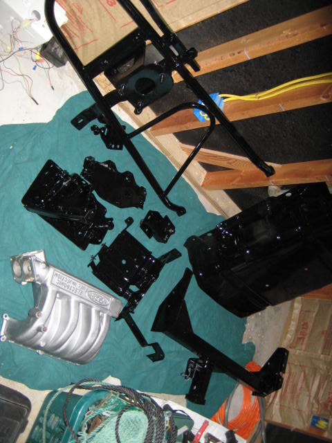 1988 Ford Bronco - Various painted frame components and a silver intake manifold are laid out, suggesting preparation for assembly or repair.