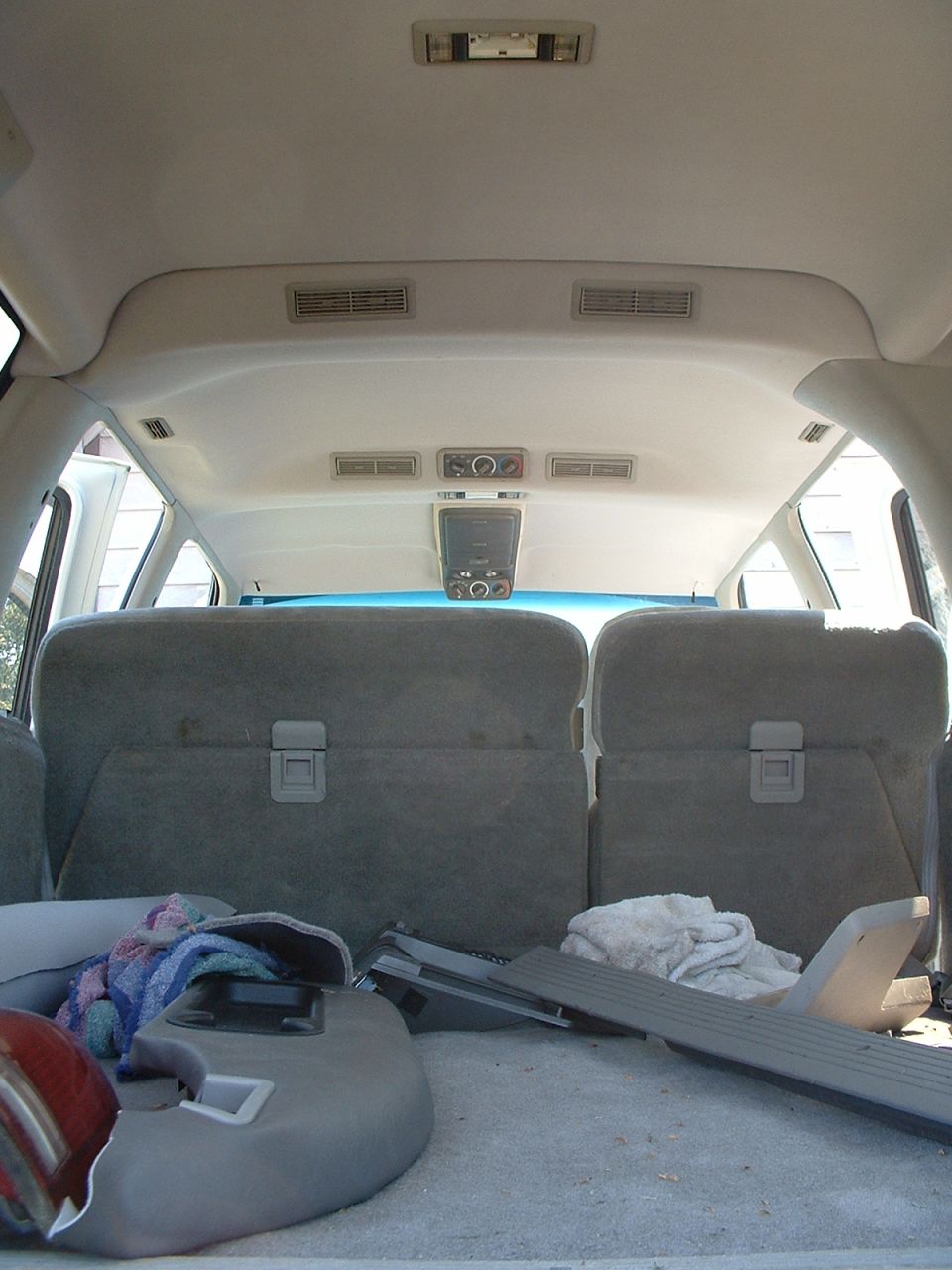 SUV cargo area with gray rear bench seats and loose trim panels on the floor