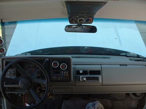 1994 GMC Suburban - The dashboard of a vehicle shows aftermarket gauges and a stereo system installed.