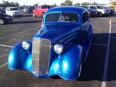 2000 Harley-Davidson FXDWGI Wide Glide - A bright blue hot rod coupe is parked in a lot with other vehicles in the background.