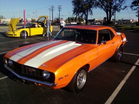 2000 Harley-Davidson FXDWGI Wide Glide - A bright orange 1969 Chevrolet Camaro Z/28 with white racing stripes is parked at a car show, with a yellow Chevrolet Corvette in the backg…