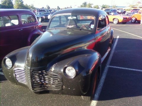 2000 Harley-Davidson FXDWGI Wide Glide - A black vintage car is parked in a lot next to a purple car, with other vehicles in the background.