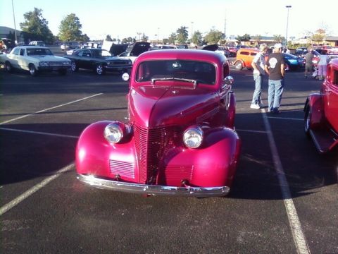 2000 Harley-Davidson FXDWGI Wide Glide - A bright red vintage coupe is parked at a car show with other vehicles visible in the background.