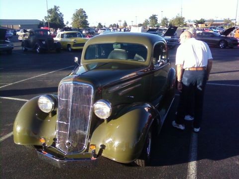 2000 Harley-Davidson FXDWGI Wide Glide - A vintage coupe is displayed at an outdoor car show with other vehicles present.