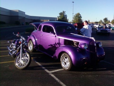 2000 Harley-Davidson FXDWGI Wide Glide - A purple vintage coupe and a motorcycle are parked in a lot. The car's hood is open, and a man is standing nearby.