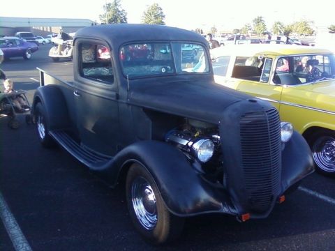 2000 Harley-Davidson FXDWGI Wide Glide - A black hot rod pickup truck is parked at an outdoor event next to a yellow car.