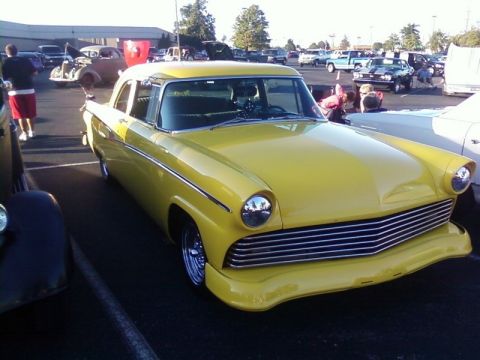2000 Harley-Davidson FXDWGI Wide Glide - A yellow classic car is parked in a lot with other vehicles and people around.