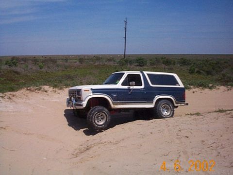 1986 Ford Bronco - This 1986 Ford Bronco is seen off-road on a sandy dune under a clear blue sky.