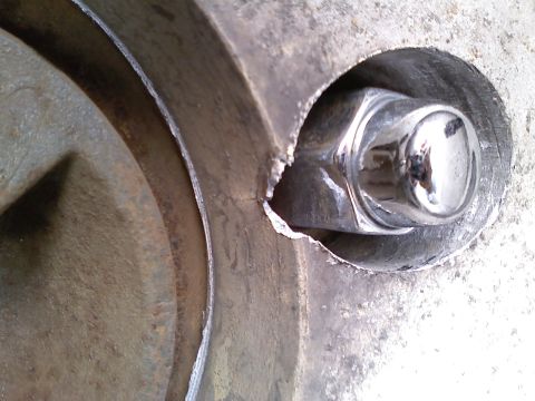 1990 Ford Bronco - A close-up view shows a shiny lug nut secured within a heavily textured, possibly damaged, metal component.