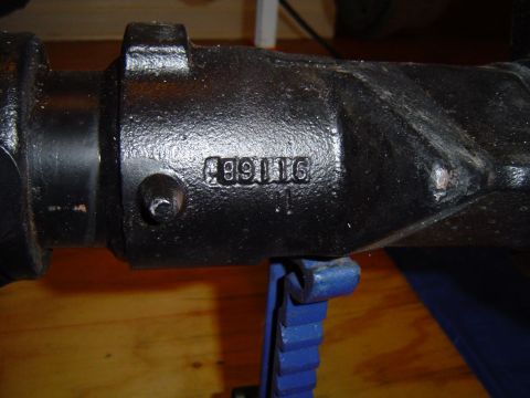 1995 Ford Bronco - This close-up shows casting numbers on a vehicle axle housing, which is supported by a blue jack stand.