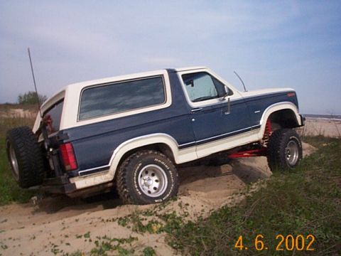 1986 Ford Bronco - Ford Bronco navigates sandy terrain near the ocean, its off-road capabilities.