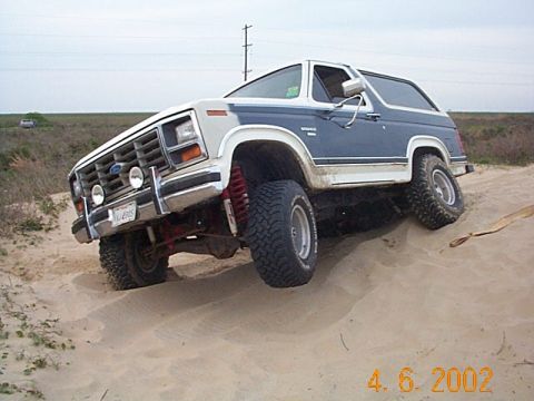 1986 Ford Bronco - This Ford Bronco is navigating a sandy terrain with its front wheels angled.