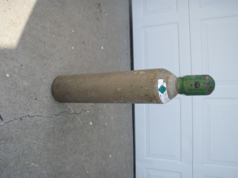 1994 Ford Bronco - A gas cylinder with a green cap and hazard labels is shown lying on a concrete surface.