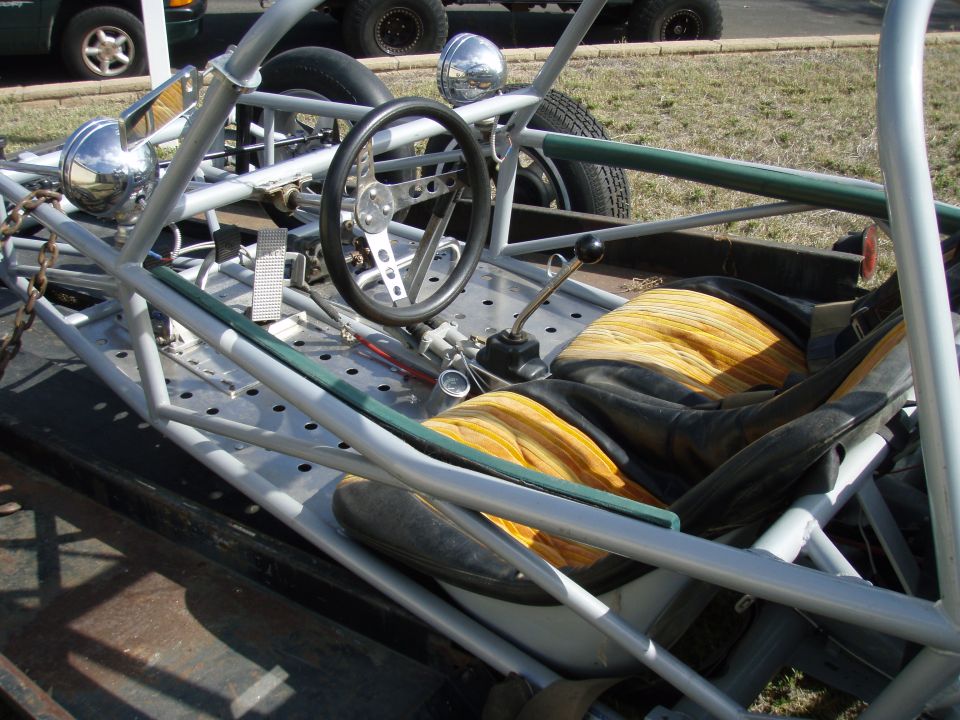 Cockpit of a tube-frame sand rail with three-spoke wheel, shifter and yellow-striped bucket seats