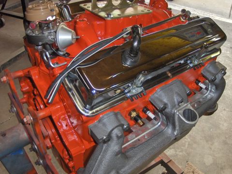 1970 Chevrolet Camaro - Close-up of a V8 engine, a chrome valve cover and orange block, with exhaust manifolds visible.