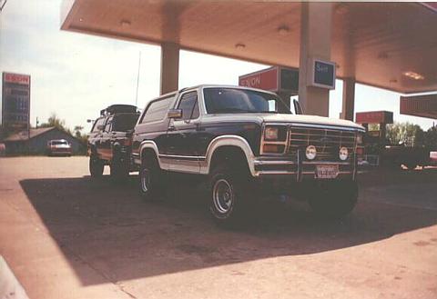 1986 Ford Bronco - A lifted Ford Bronco and another SUV are parked at a gas station under the canopy.