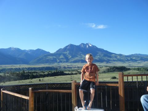 1981 Ford E350 - A young boy poses on a wooden deck railing with a scenic mountain landscape under a clear blue sky.