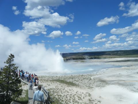 1981 Ford E350 - Tourists gather on a boardwalk to witness a geyser erupt in a geothermal area.