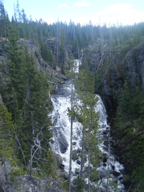 1981 Ford E350 - A waterfall flows through a rocky, forested canyon.
