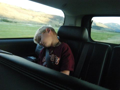1981 Ford E350 - A young boy sleeps in the back seat of a vehicle while traveling through a rural landscape.