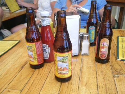 1981 Ford E350 - Bottles of beer and ketchup are arranged on a wooden table, with people visible in the background.