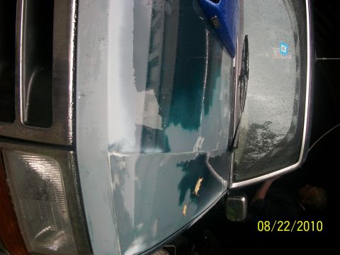 1993 Ford Bronco - Close-up of a vehicle's front fender and headlight, showing areas of primer and peeling paint.