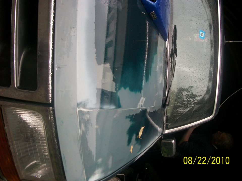 Front fender and headlight of a 1993 Ford Bronco with peeling paint and primer showing