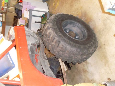 1985 Jeep CJ7 - Close-up of an orange Jeep CJ fender and a large off-road tire, with a Honda decal in the background.