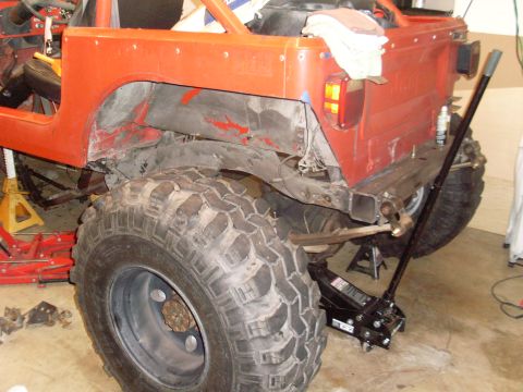 1985 Jeep CJ7 - The rear of a Jeep CJ is shown elevated on jack stands, revealing its suspension and large tires.