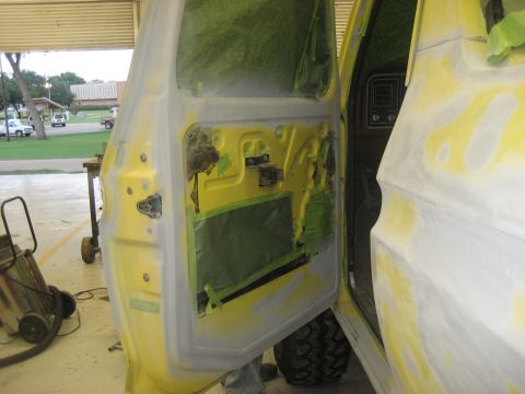 1978 Ford Bronco - The interior of a 1978 Ford Bronco's door and body panel are shown, covered in primer and tape, ready for paint.