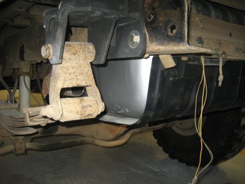 1978 Ford Bronco - The underside of a vehicle reveals a fuel tank and suspension parts, with visible wiring and rust.