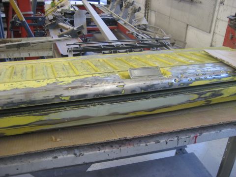 1978 Ford Bronco - A yellow tailgate is shown in a workshop, undergoing repairs or preparation.