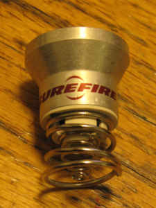 1984 Ford Bronco - A close-up of a Surefire flashlight component, a visible spring and the Supermotors website address.